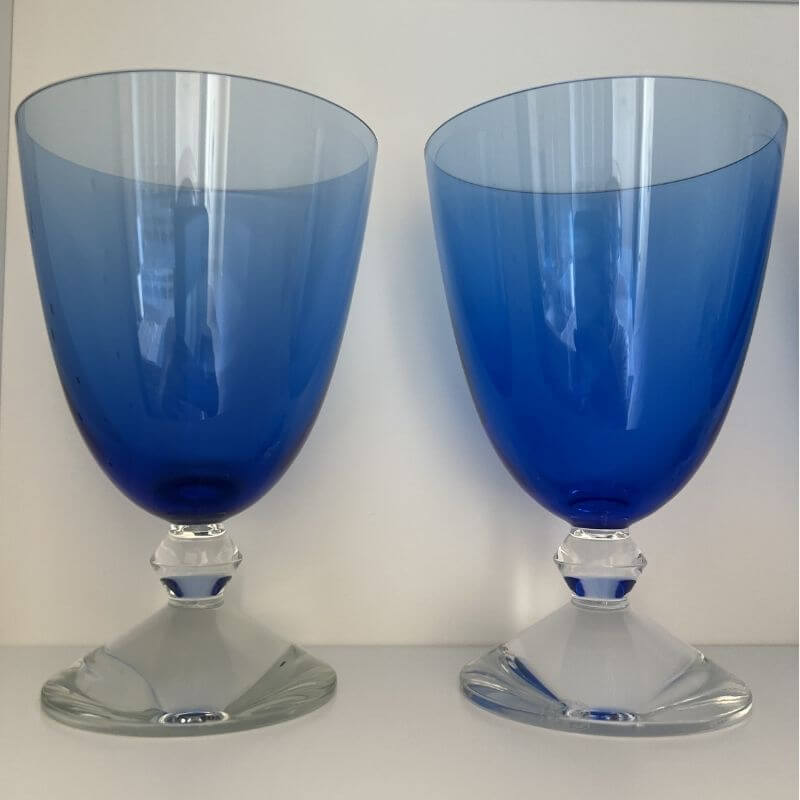 Elegant blue crystal water goblets with clear stems showing luxury colored glassware for formal table settings