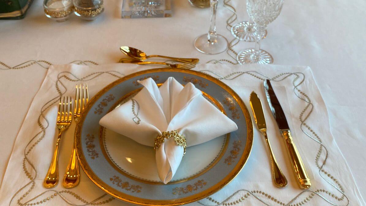 Elegant fan napkin fold with gold ring on blue and gold china with crystal glassware