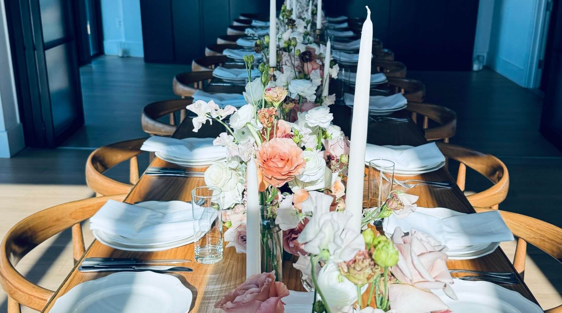 Flower arrangement for dining table with bud vases, candles, and place settings at an elegant dinner party