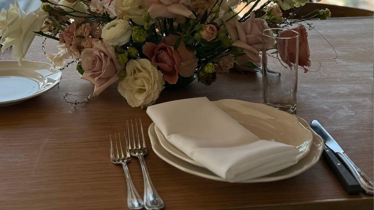 Simple rectangle napkin fold on white plate with roses and elegant place setting