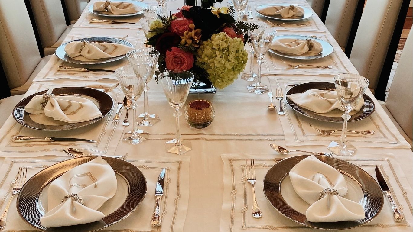 Elegant dinner party checklist table setting with silver chargers, crystal glassware, and floral centerpiece