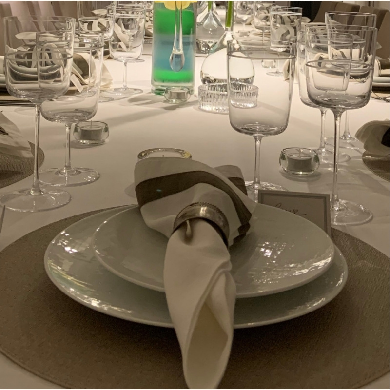 Elegant dinner party place setting with charger plate, folded napkin, and wine glasses