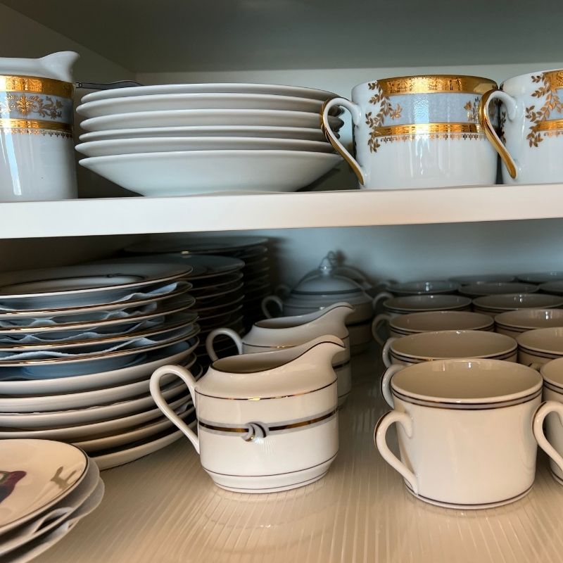Organized dinnerware and teacups in cabinet for dinner party planning checklist inventory