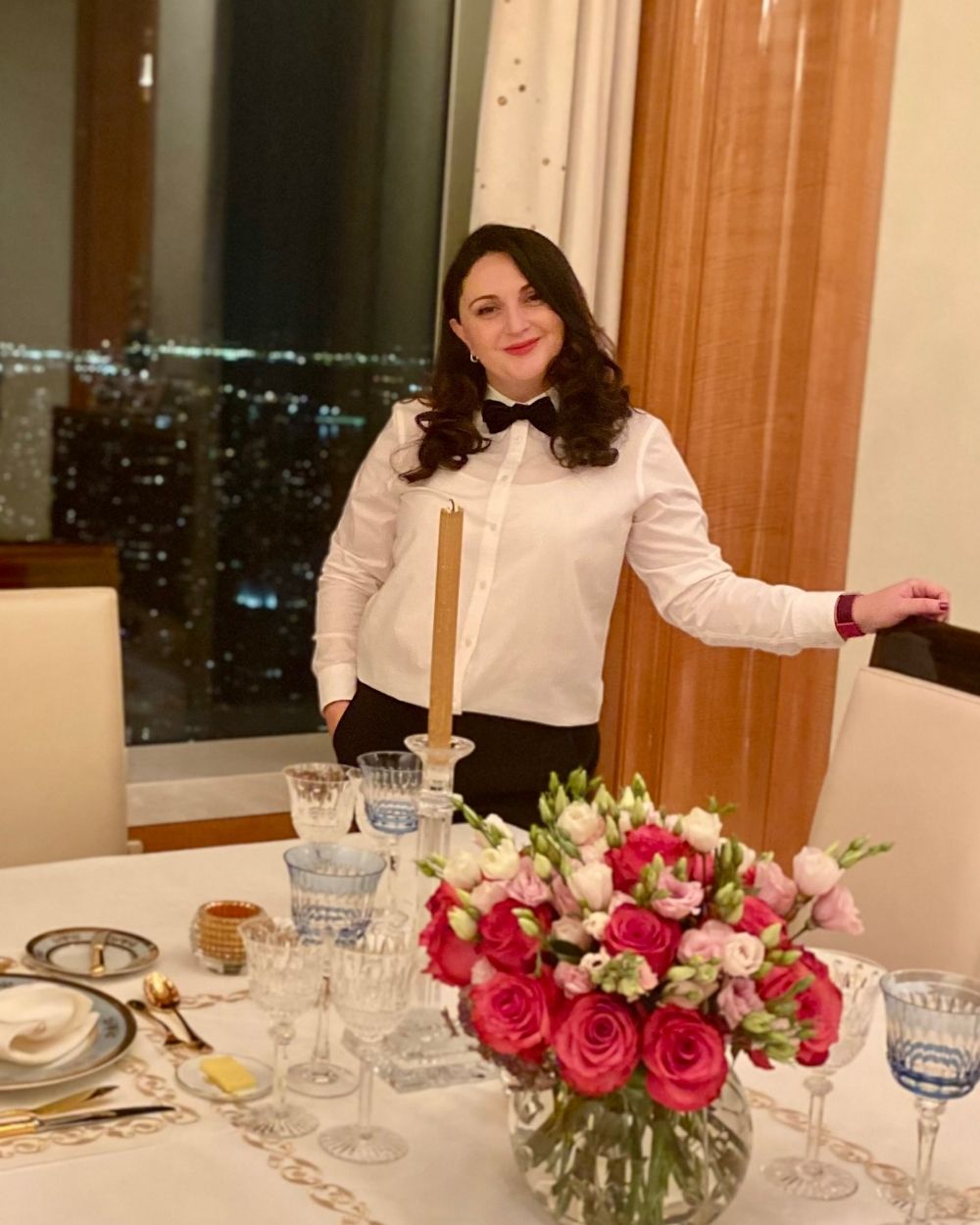 Nino Meekma in white-glove service attire at a private New York dinner setting with red roses and crystal glassware