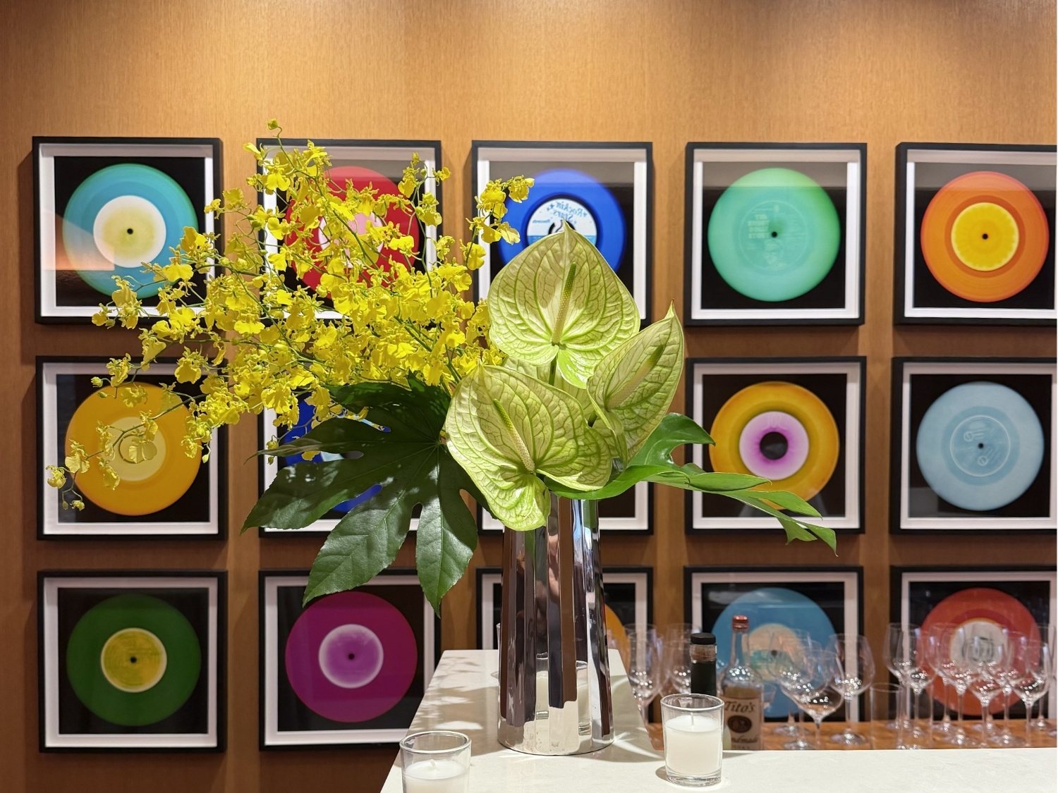 Bar cart styled with a tall yellow orchid and anthurium arrangement beside glassware