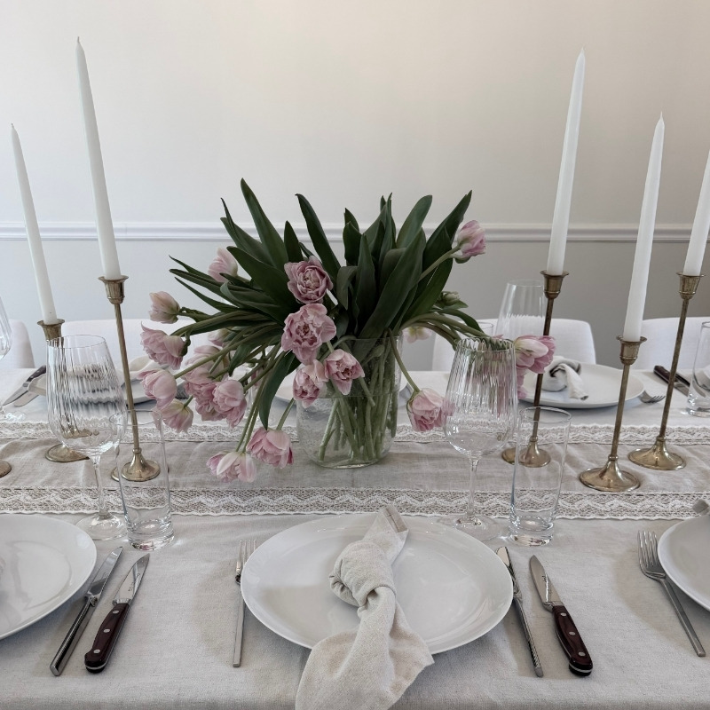 Finished dinner party table set with candlelight, florals, and considered ambiance