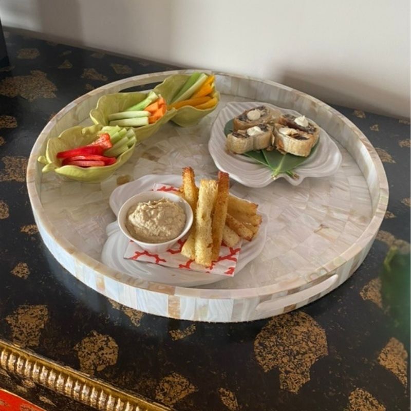 Round mother of pearl serving tray holding crudites, dips and small appetizer plates