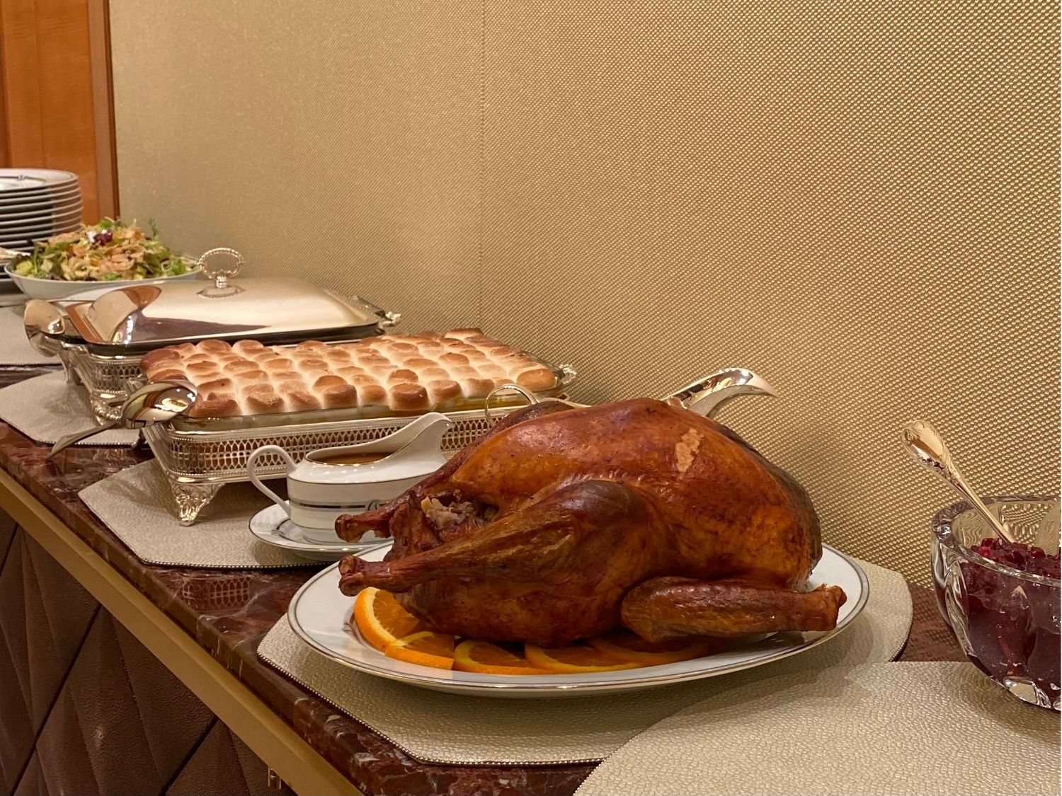 Silver chafing dishes and a white oval platter with roast turkey on a holiday buffet