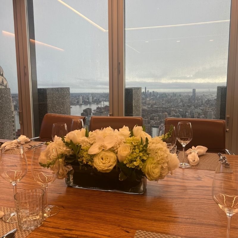 Low centerpiece seen at seated eye level across a wooden dining table