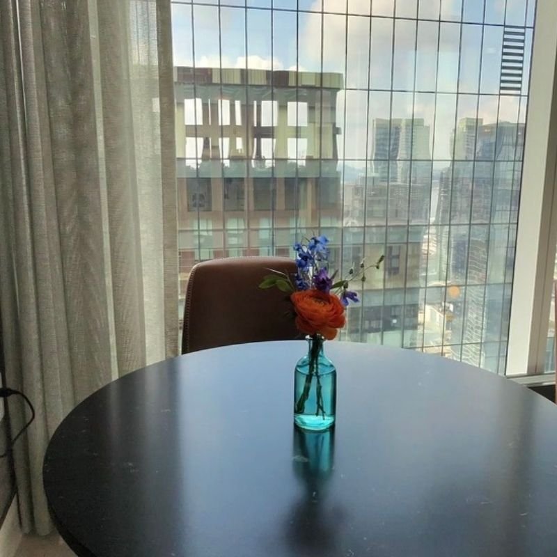 Small vase with a single ranunculus and delphinium kept to the center of a round table